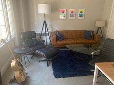 a living room filled with furniture and a guitar on the floor next to a window