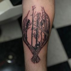 a man's arm with a deer and trees tattoo on it