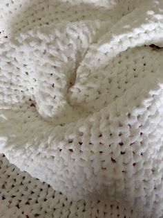 a white crocheted blanket laying on top of a bed