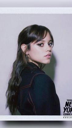 a young woman with long hair standing in front of a wall