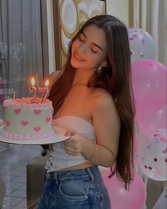 a woman holding a cake with lit candles