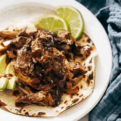 a close up of a plate of food with meat and limes on the side