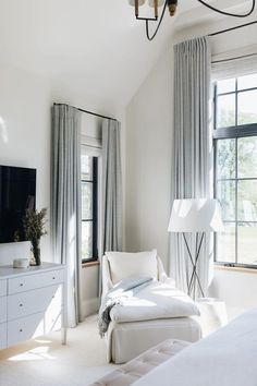 a living room with white furniture and large windows