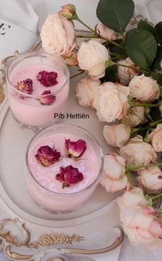 two glasses filled with pink liquid next to flowers on a white plate and gold trim