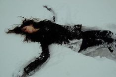 a woman laying in the snow on her back