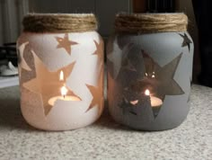 two mason jars with candles in them sitting on a counter