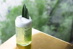 a glass bottle with a green leaf sticking out of it's top sitting on a table