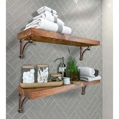 two wooden shelves with towels and other items on them in a bathroom wallpapered with herringbone tiles