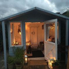 a small blue house with lights on the front door and windows open to let in some light