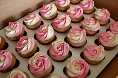 a box filled with pink and white cupcakes on top of a table next to each other