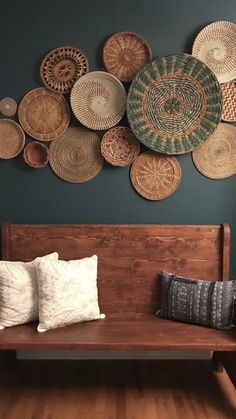 a wooden bench sitting in front of a wall with baskets hanging on it's side