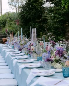 a long table is set up with blue and white linens for an outdoor dinner