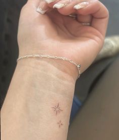 a woman's wrist has a tiny star tattoo on it, while the rest of her arm is visible