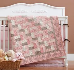 two teddy bears sitting in a basket next to a baby quilt