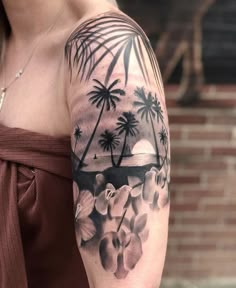 a woman's arm with flowers and palm trees on it