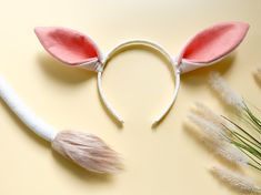 a bunny ears headband with pink fur on it and some white feathers next to it