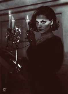 a woman holding a candle in her hand and looking at the camera with an evil look on her face