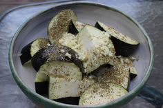 a bowl filled with sliced up eggplant and seasoning sprinkled on top