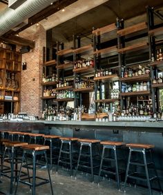 an empty bar with stools and bottles on the shelves