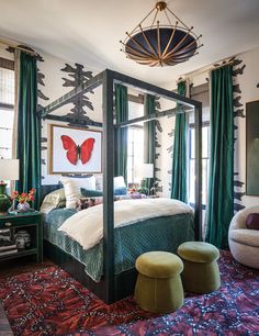 a bedroom with a canopy bed, green curtains and colorful rugs on the floor