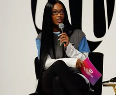 a woman sitting in a chair holding a microphone