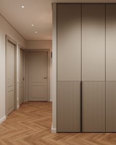 an empty room with wooden flooring and white closet doors on the wall, in front of a wood parquet floor