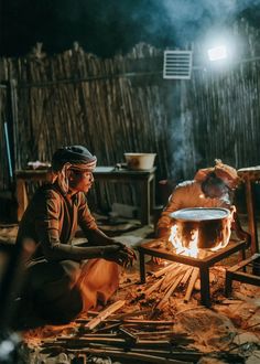 two people sitting around a fire pit in the dark