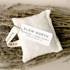 a white pillow sitting on top of a pile of dried lavender next to a tag that says slow north