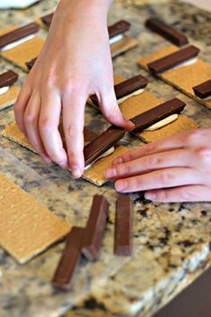 two hands reaching for chocolate squares on top of a counter