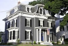 a large gray house with white trim and black shutters