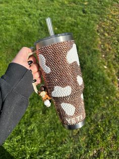 a person holding a cup in their hand on top of green grass with white dots