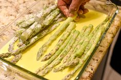 someone is peeling asparagus in a glass dish on the kitchen counter with yellow liquid