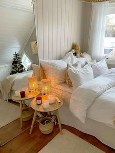 a bedroom with white bedding and candles on the table