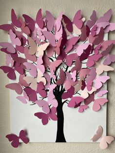 a tree made out of paper with pink and purple butterflies flying around it on the wall