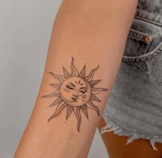 a woman's arm with a sun and moon tattoo on the left side of her arm