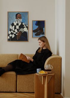 a woman sitting on a couch reading a book