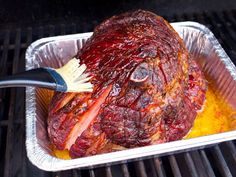 a large piece of meat is being cooked on the grill with a brush in it