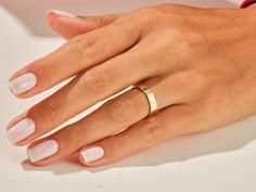 a woman's hand with two gold rings on her left and one pink manicured