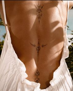 the back of a woman's body with tattoos on it