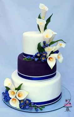 a three tiered cake with white and blue flowers