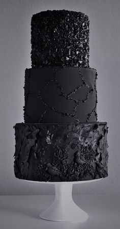 three tiered cake with black frosting and sprinkles