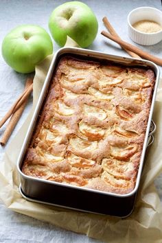 an apple cobbler with apples and cinnamon sticks around it on a white tablecloth