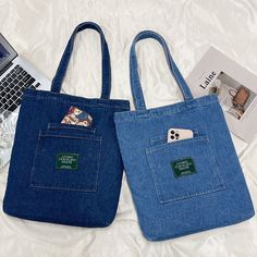 two blue bags sitting on top of a bed next to a laptop