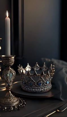 a candle is lit next to a silver crown on a black table with other items