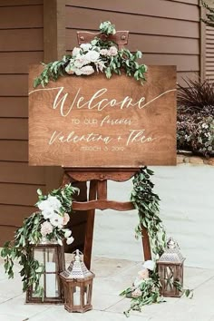 a welcome sign with flowers and greenery on it