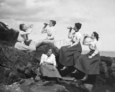 four women are sitting on rocks and drinking from bottles