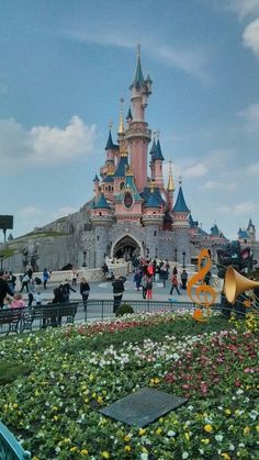 people are walking around in front of a castle with musical instruments and flowers on the ground