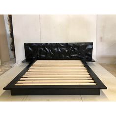 a bed with wooden slats and black leather headboard