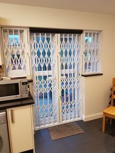 a kitchen with an oven, microwave and table in front of glass doors that are open