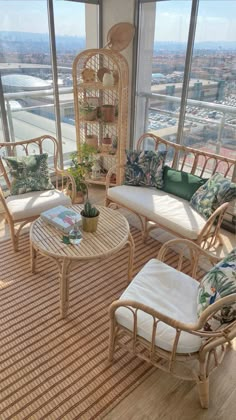 a living room with wicker furniture and large windows looking out on the cityscape